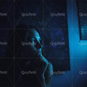 A contemplative woman sits in a room dimly lit with blue light.